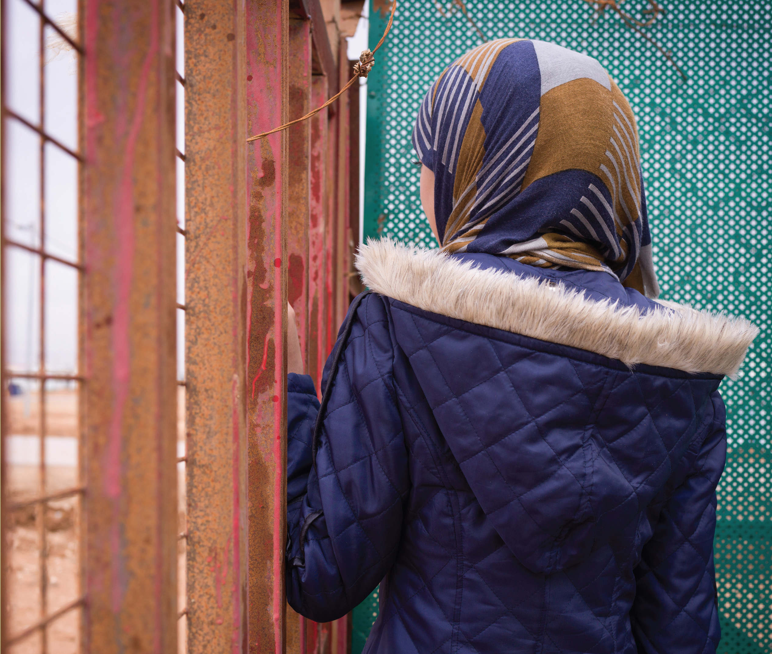 A girl in a multicolored hijab looks away from the camera.