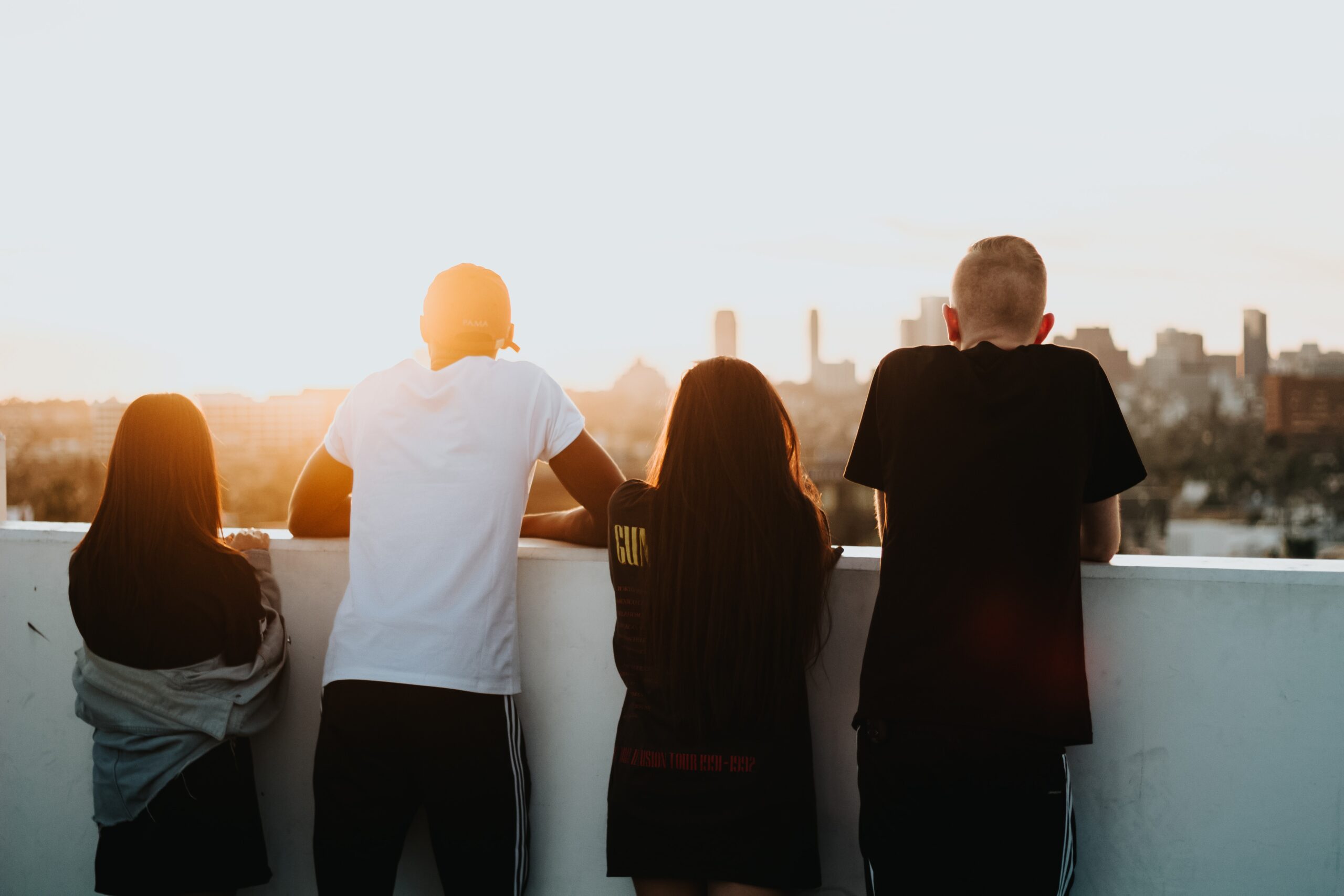 Four young people look out at a city skyline. Their faces are not in view.