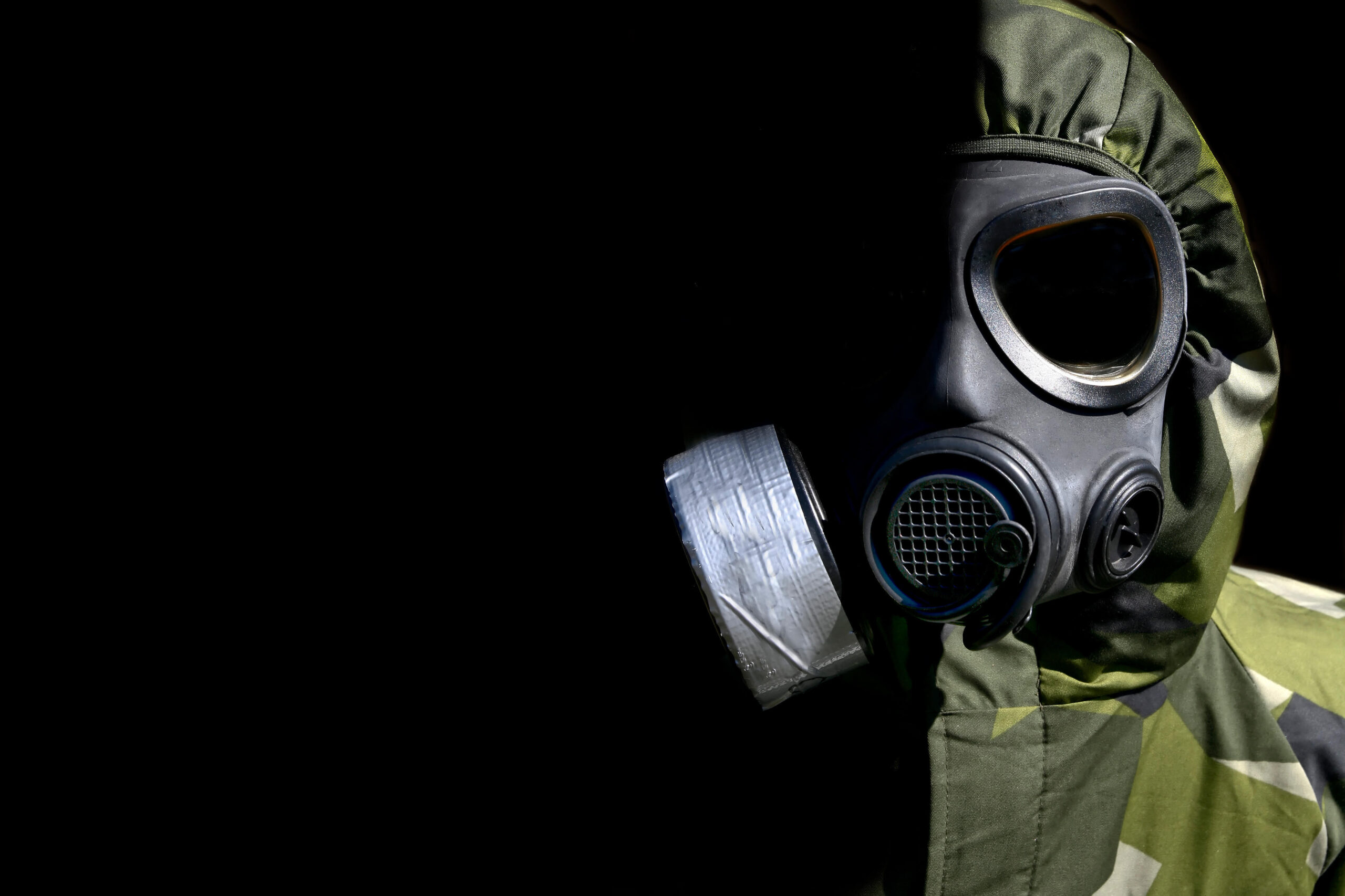 Military person wearing a gasmask and protective clothing.