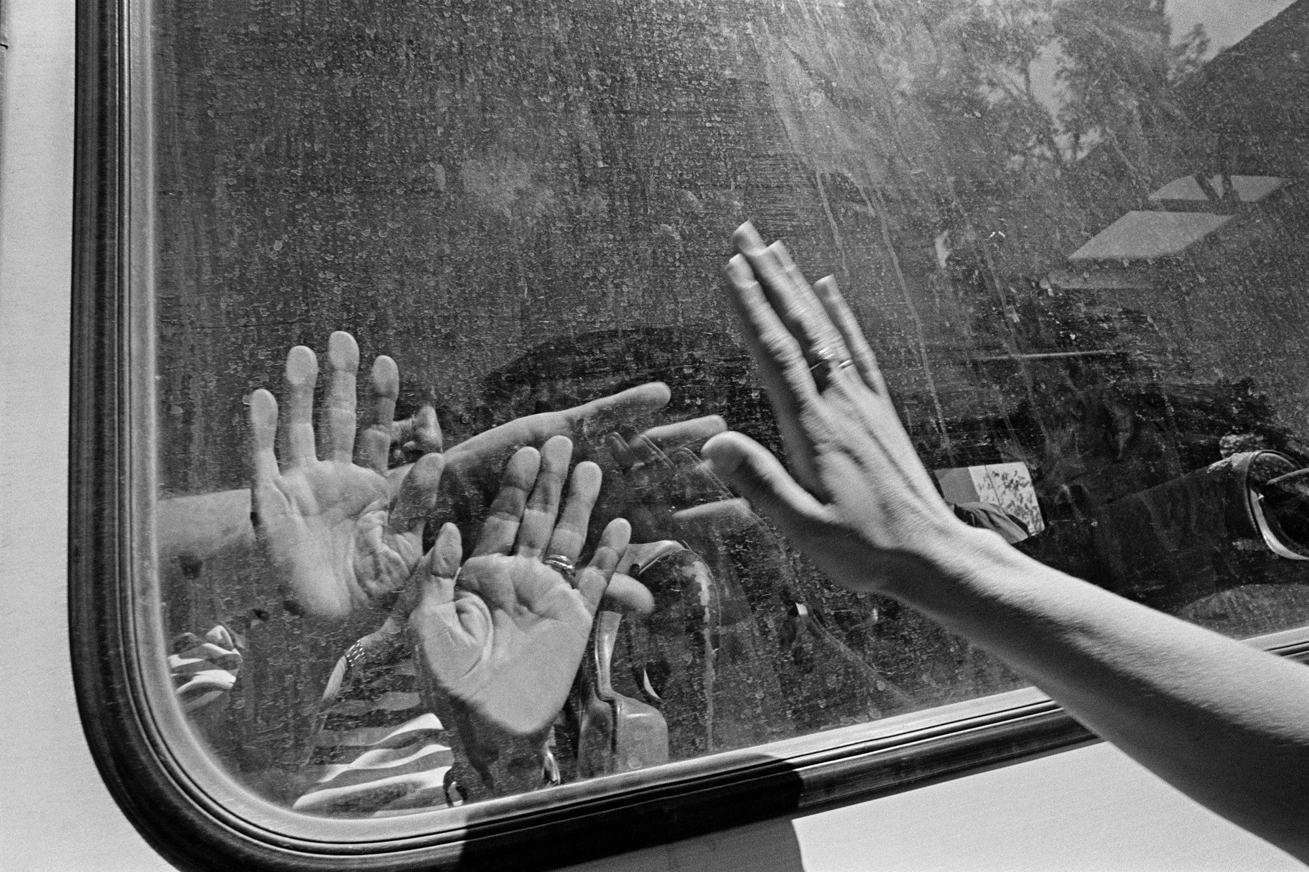 Hands pressed against a pane of glass meet hands on the other side.