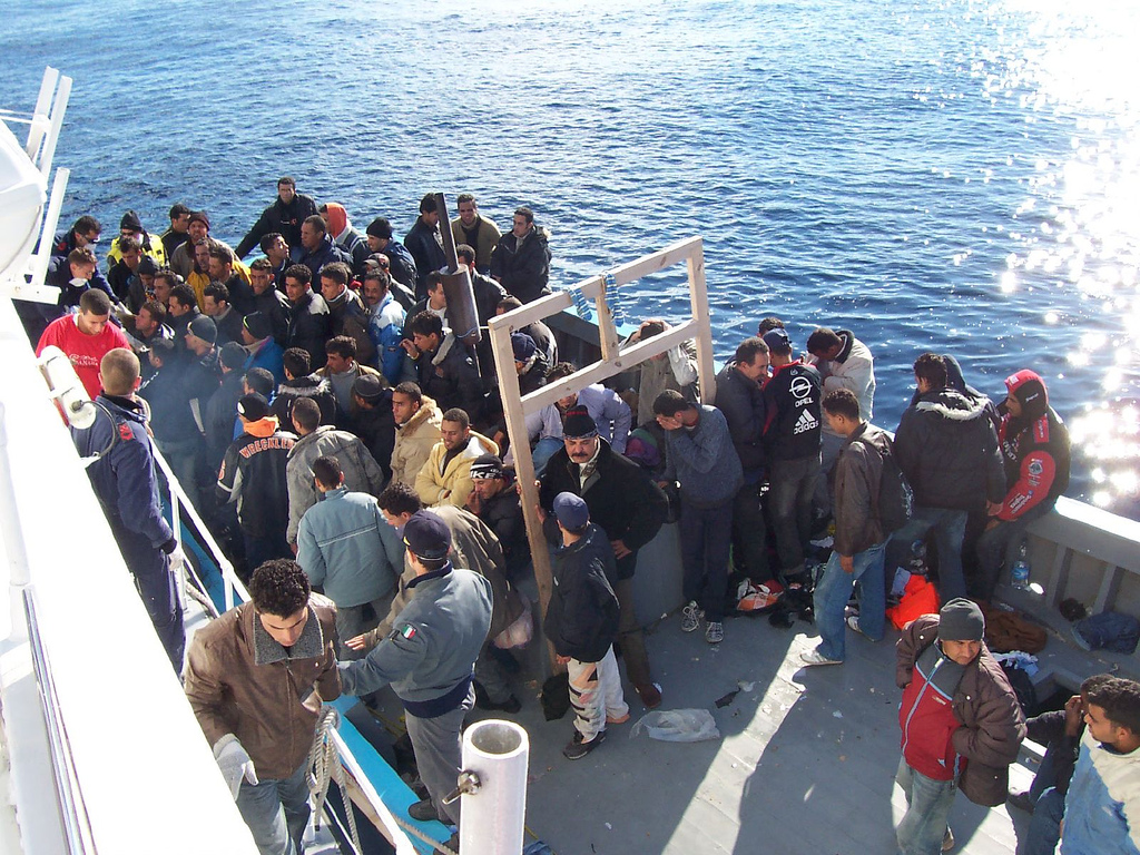 A group of people congregate on a ship in the ocean.