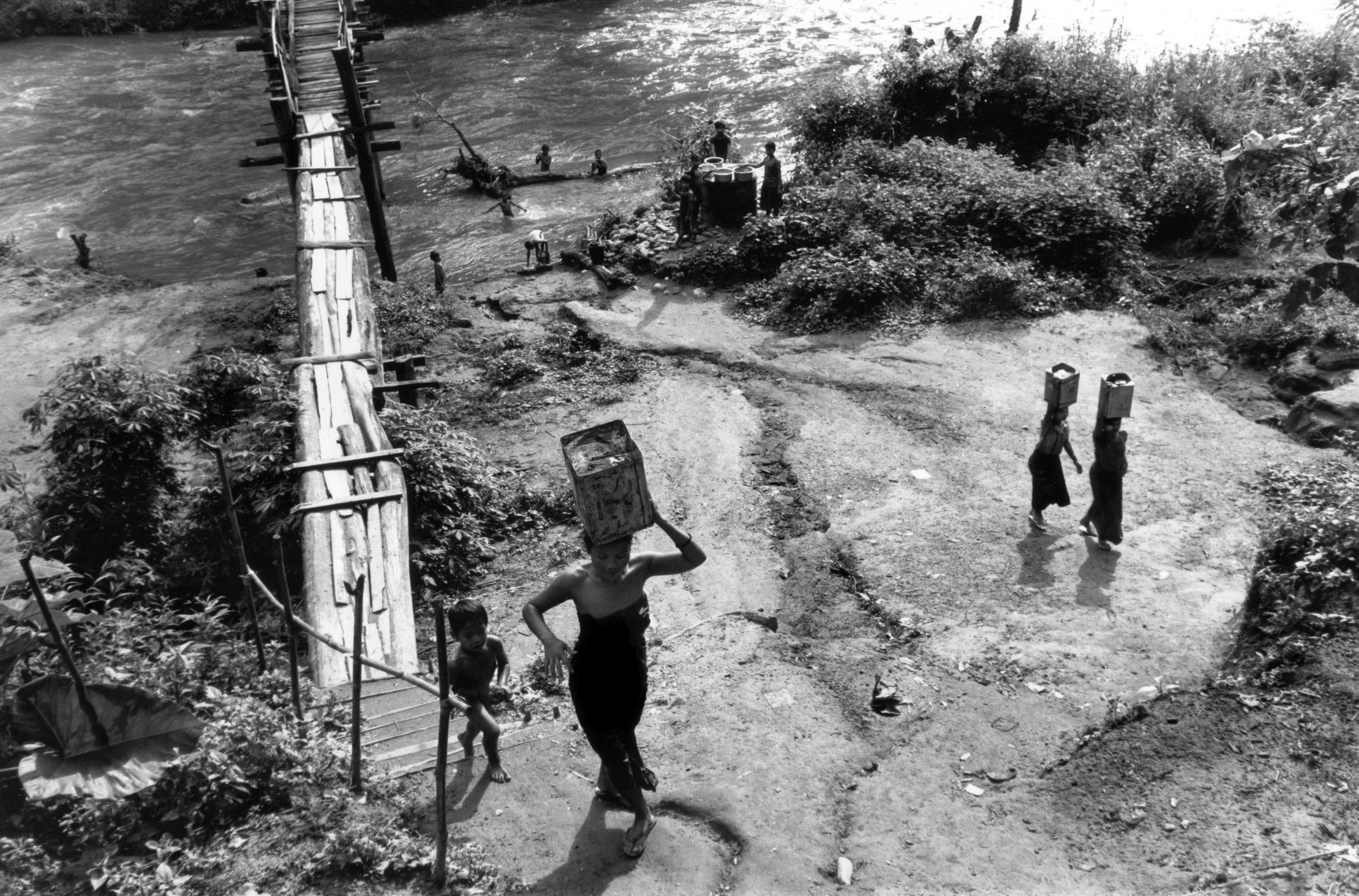 People carry water in jerrycans on their heads from a nearby river.
