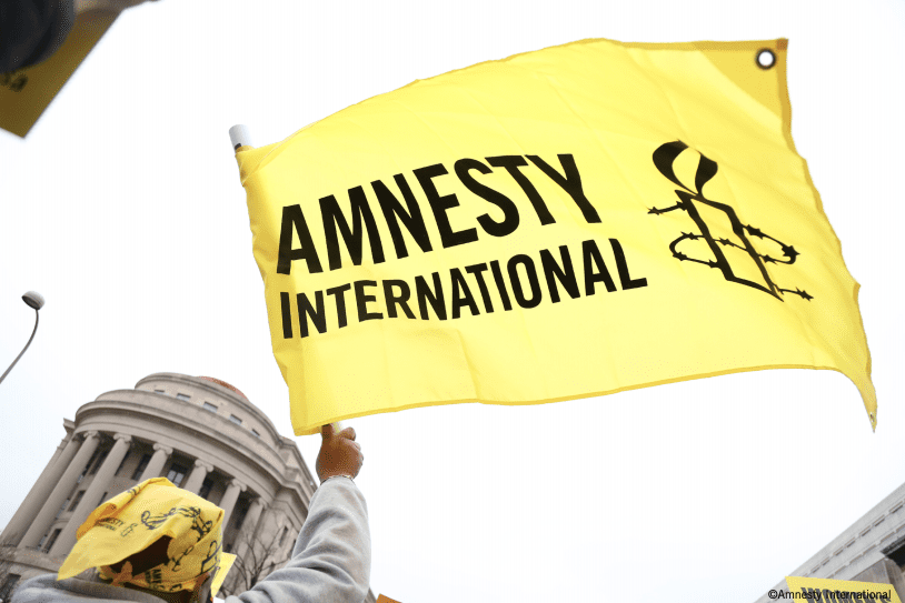 Amnesty International flag, showing a candle surrounded by barbed wire and the words 