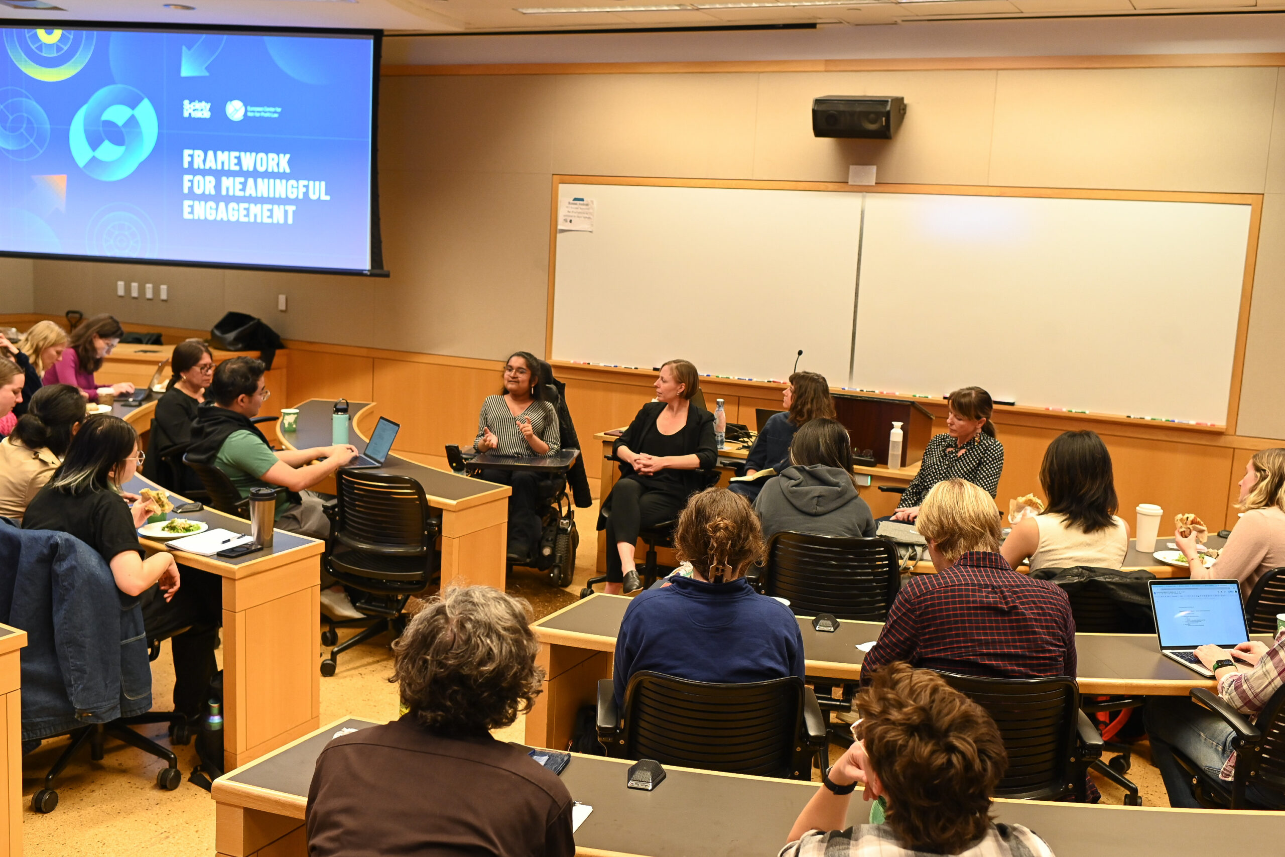 Four panelists speak to a crowd of students in a university room.