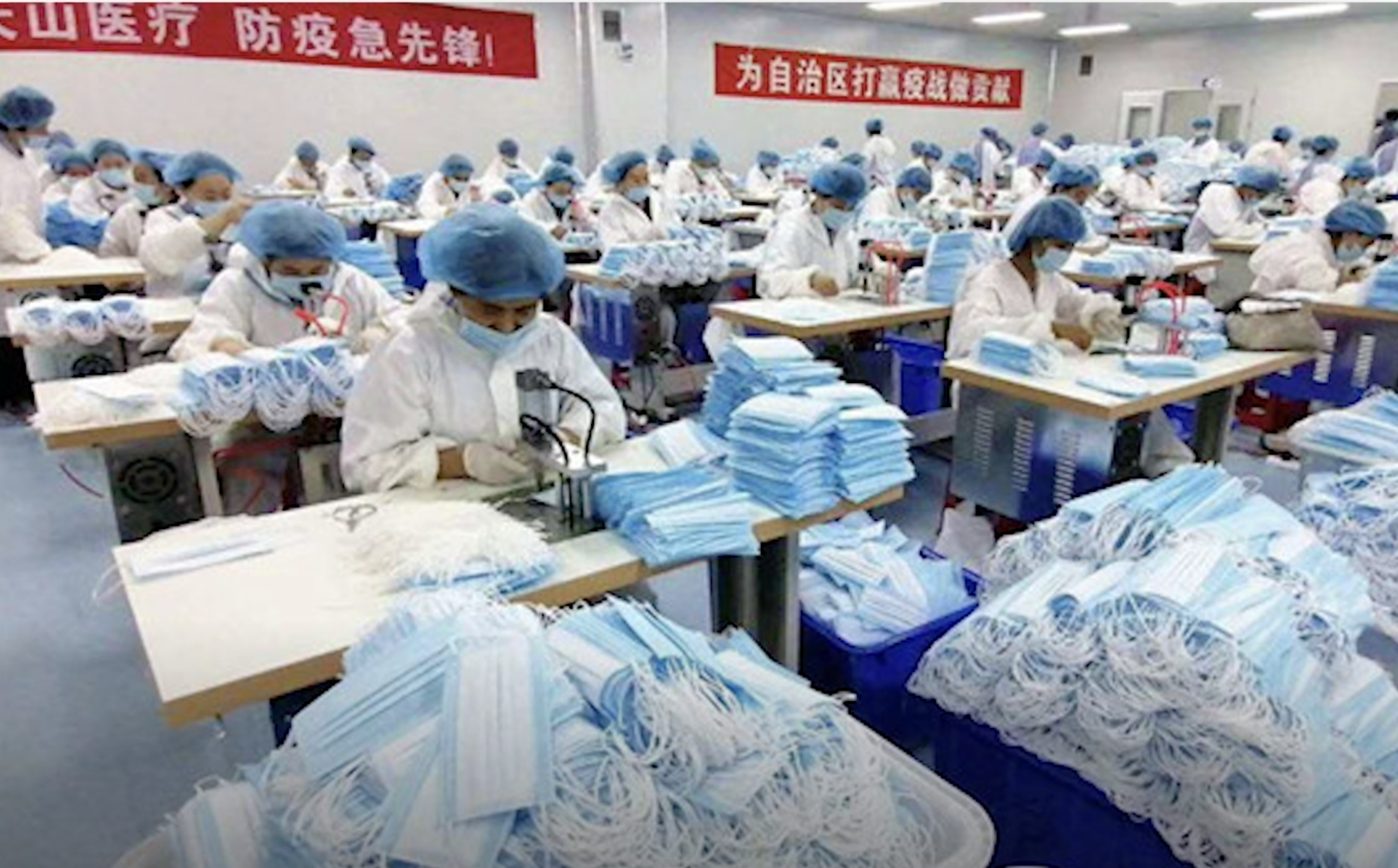 People make masks in a factory, Chinese lettering is present.