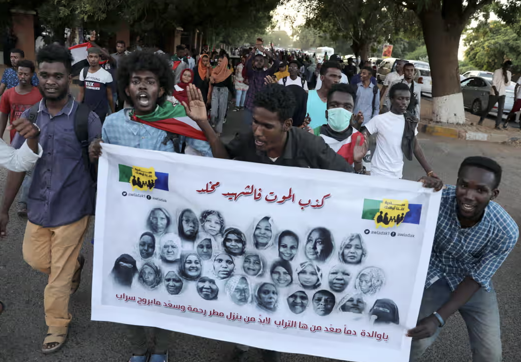 A group of people march in the street with a sign depicting protestors allegedly killed in unrest in Khartoum in June 2019.
