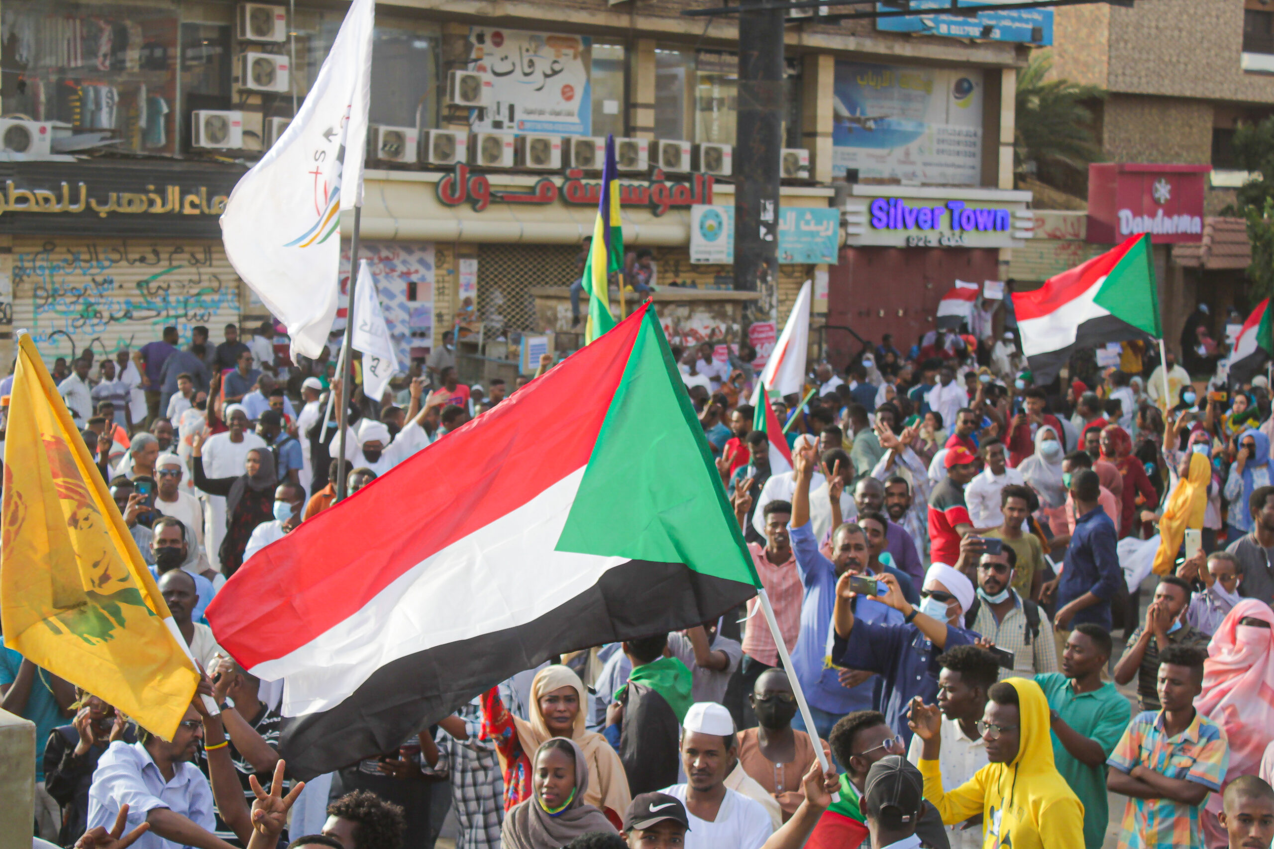 A group of people fill the streets and wave the Sudanese flag.