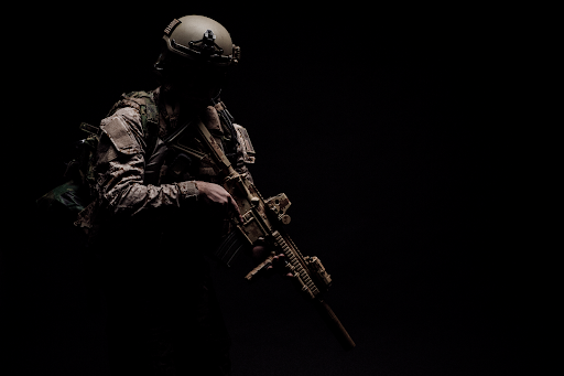 A soldier shrouded in darkness carries a weapon.