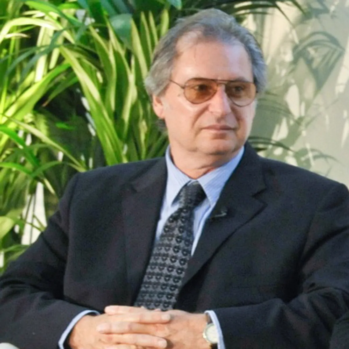A man with glasses and grey hair sits.