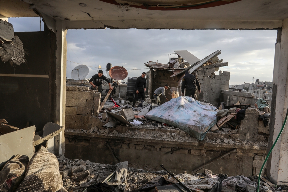 A group of people inspect the ruins of a house that was destroyed by an air strike.