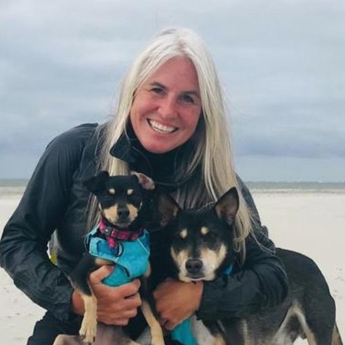 A woman with two dogs smiles at the camera.
