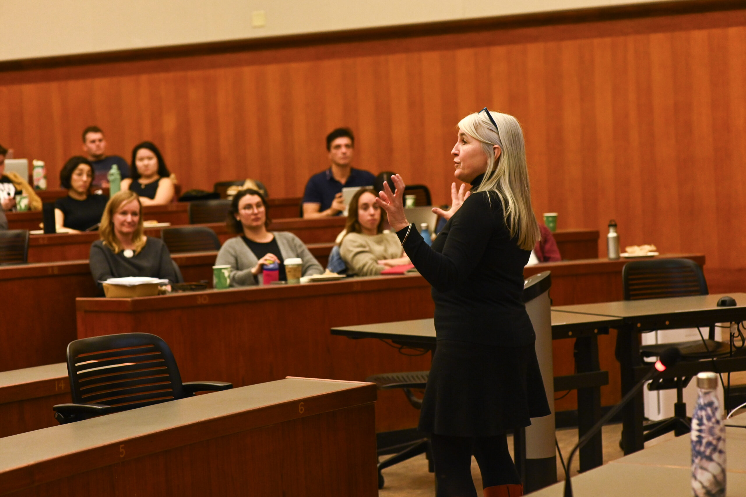 A woman speaks to several students.